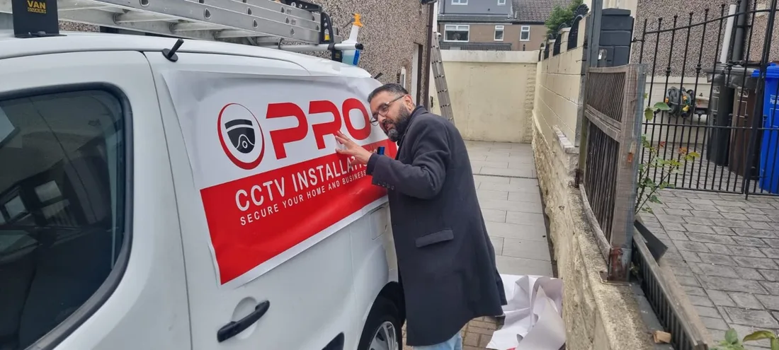 Imran from Web Print Signs fitting red printed graphics to a CCTV installer's van
