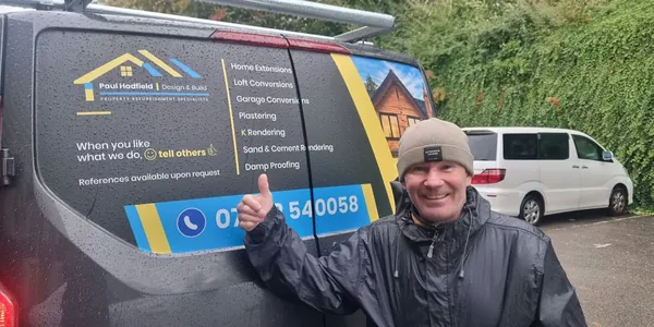 Paul Hadfield giving a thumbs up beside the rear door graphics on his dark grey Ford van