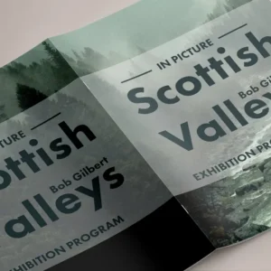 Open saddle stitched exhibition booklet showing the stapled spine